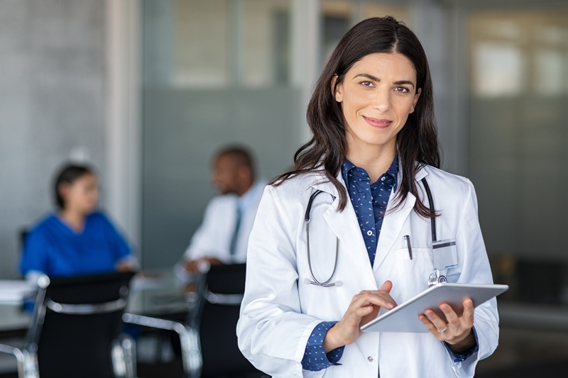 Female bioidentical doctor holding tablet, with stethoscope around her neck